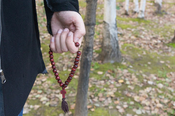 Wooden monastic rosary with a crucifix in a male hand. Perhaps a Christian, pastor or preacher.