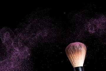 cosmetic brush and sprayed cloud of cosmetics on a black background