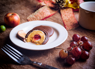 Chocolate pie with marshmallow and jam on white plate, apples , grapes  and coffee cup on table.  Christmas morning coffee.