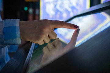 Woman using interactive touchscreen display of electronic multimedia kiosk at modern museum or...