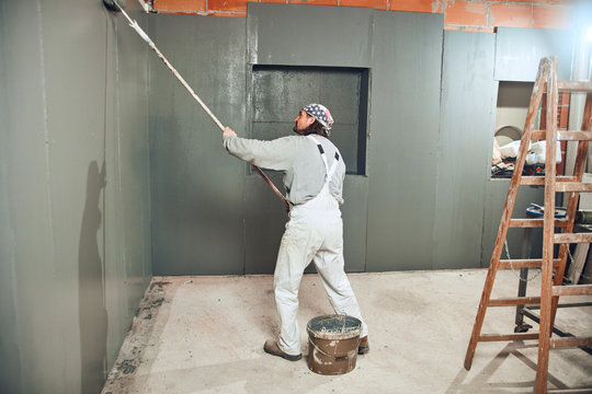 Painter painting walls with a extender roller indoors.