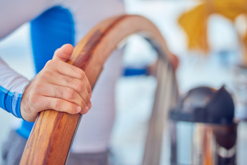 Sailor using wheel to steer rudder on a sailing boat. © astrosystem