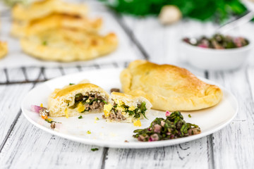Some Empanadas on a vintage wooden table (selective focus; close-up shot)
