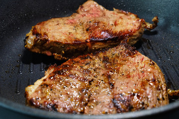 Two pieces of beef fried in a black skillet grill. Grill meat pan. Cooking a beef steak. 