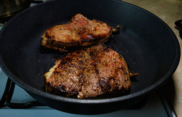 Two pieces of beef fried in a black skillet grill. Grill meat pan. Cooking a beef steak. 