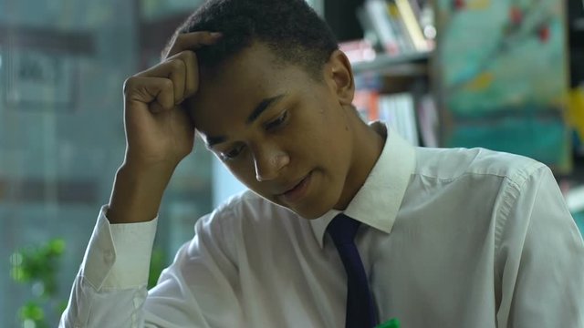 Puzzled schoolboy thinking over complicated test in classes, unprepared for exam