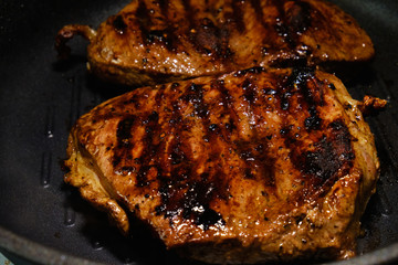 Two pieces of beef fried in a black skillet grill. Grill meat pan. Cooking a beef steak. 