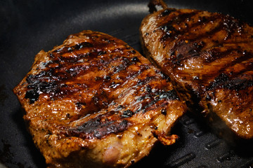 Two pieces of beef fried in a black skillet grill. Grill meat pan. Cooking a beef steak. 