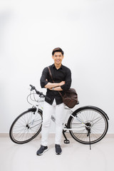 A young stylish man posing next to his bicycle.