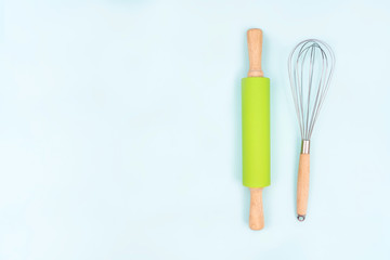 Kitchen utensils and baking accessories on blue background with copy space. Rolling pin and whisk for cooking. Set for mock ups and bakery design. Flat lay.