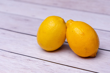 two lemons on a white wooden background