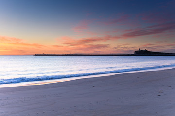 Sunrise over Nobbys Headland and Lighthouse viewed from Stockton Beach