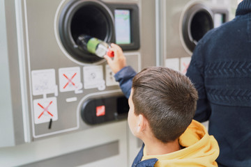 Child recycling plastic bottles in a machine