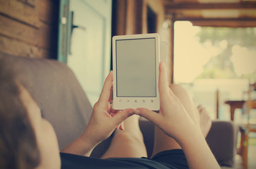 Caucasian woman reading ebook on couch. Copy space. Selective focus on hands and book.