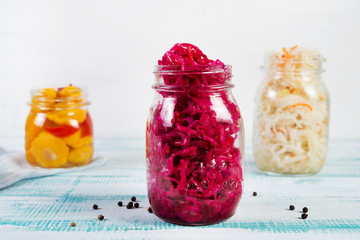 Fermented vegetables in jars. Sauerkraut, pickled beets and pickled squash on a light wooden...