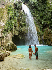 lovely couple alone in deep forest waterfall from mountain gorge at hidden tropical jungle Inambakan Falls in Cebu Island in Philippines