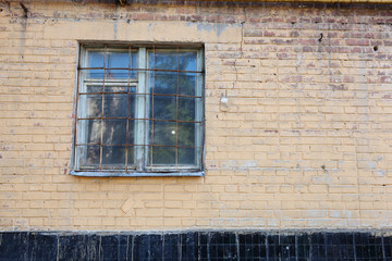Vintage old window with lattice metal bars on the wall facade