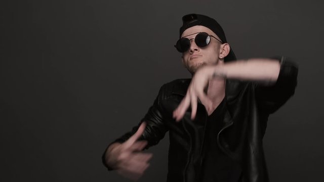 Talented young man performing cool dance. Stylish man in glasses emotionally dancing. Caucasian man dancing in studio. Contemporary dance. Krump. Hip hop style, listening to music