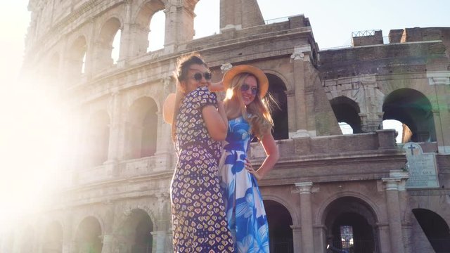 Three happy young women friends tourists with bikes taking selfies at Colosseum in Rome, Italy at sunrise.