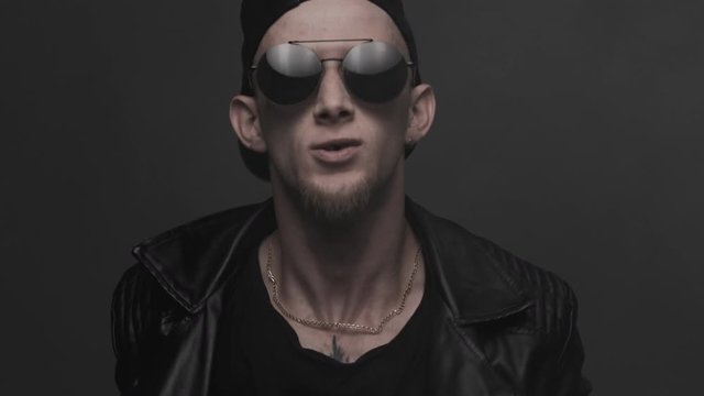 Aggressive man exhaling smoke. Dancing young man performing various freestyle dance moves. Stylish man in glasses emotionally dancing. Contemporary dance. Krump. Hip hop style, listening to music 4k