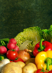 various kinds of vegetables, autumn vegetable, like peppers, tomatoes, red radishes, cabbage over green rustic  background 