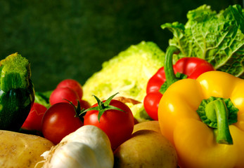 various kinds of vegetables, autumn vegetable, like peppers, tomatoes, red radishes, cabbage over green rustic  background 
