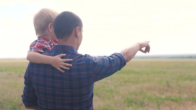 happy family. slow motion video training father and son teamwork concept. father holds his son in his arms shows into the distance his hand on the horizon nature outdoors. happy family man holds a