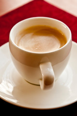 white cup with espresso coffee with beautiful foam on table 