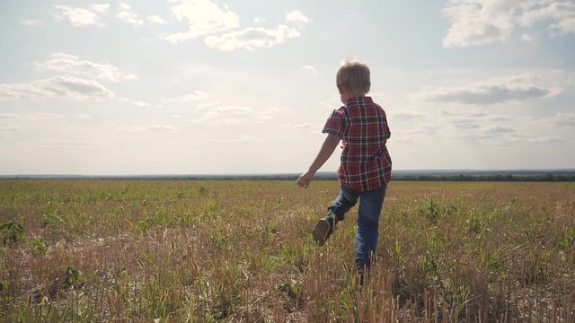 happy family concept little boy runs. boy schoolboy runs across the field lifestyle in nature slow motion video. childhood dreams of freedom superhero