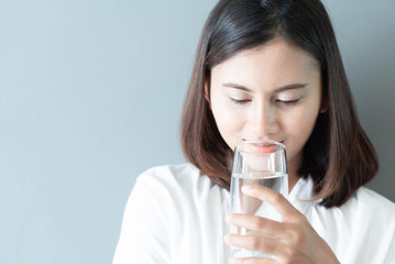Close up woman drinking pure water from glass with light in the morning, Selective focus