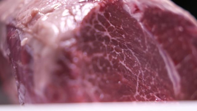 Raw marbled meat cut of beef rotating dark background