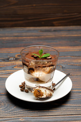 Portion of Classic tiramisu dessert in a glass cup on wooden background