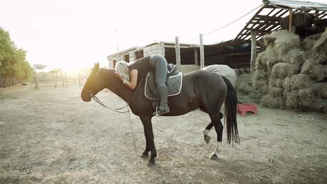 Pretty horsewoman hugs and kisses horse on countryside ranch. Concept of love, friendship, farm animals. Slow motion.