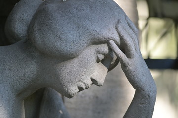 A sandstone sculpture of a thoughtful woman. A woman braces her head with her arm.