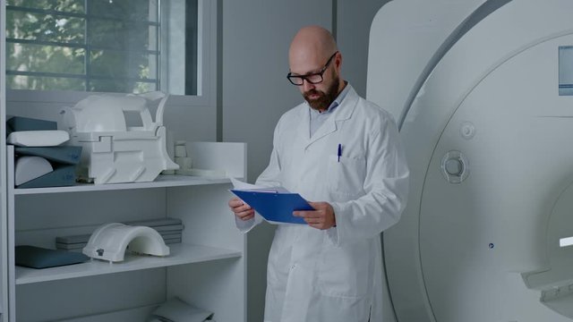 Doctor with a patient medical card near MRI scanner in a hospital