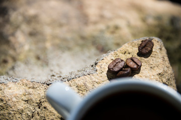 Cup of coffee and coffee beans on a stone background