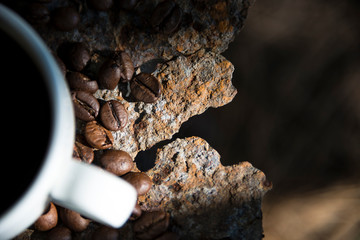 Cup of coffee and coffee beans closeup on iron rusty background