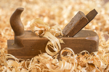 Old wooden hand plane for woodworking with wood shavings.