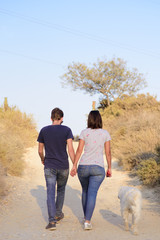 Romantic couple is on a walk in the city with their dog labrador. Beautiful young woman and handsome man are having fun outdoors with golden retriever labrador