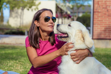 Frame with a beautiful girl with a beautiful dog in a park on green grass