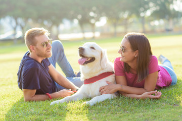 Couple lying in the park while having fun with the dog.happy family concept