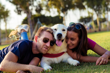Couple lying in the park while having fun with the dog.happy family concept