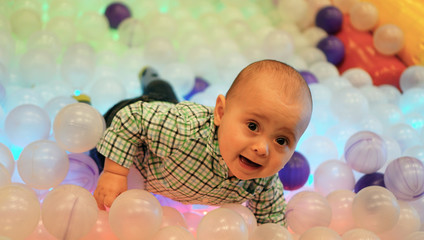 Cute toddler boy, child, playing in colorful balls in children playground