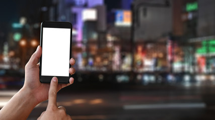 Copy space closeup hands holding mockup smartphone on Japan night city blur background.