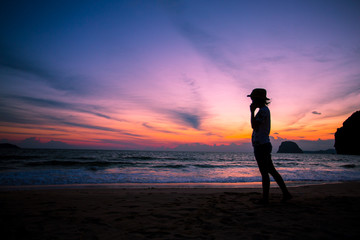 Fototapeta premium Silhouette of The girl is walking happily Use the phone at the beach during the sunset and her enjoying freedom feeling happy at sunset 