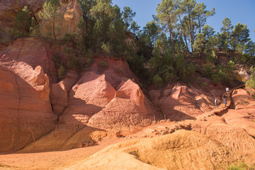 Ochre Trail in Roussillon, Sentier des Ocres, hiking path in a natural colorful area of red and yellow cliffs surrounded by green forest in Provence