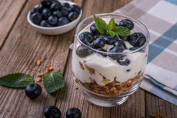 granola with yogurt and fresh blueberries in a glass  on wooden background