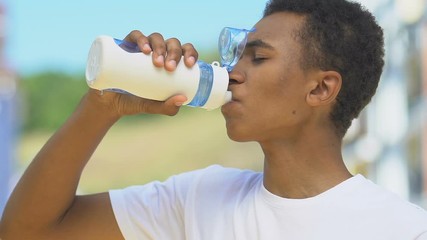 Tired male runner drinking beverage outdoor restoring water balance, refreshment