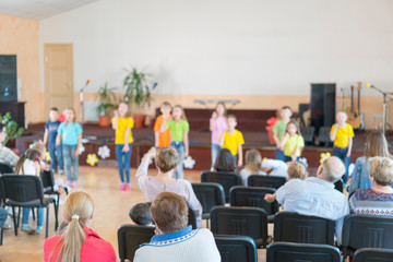 Performance by talented children. Children on stage perform in front of parents. image of blur kid 's show on stage at school , for background usage. Blurry