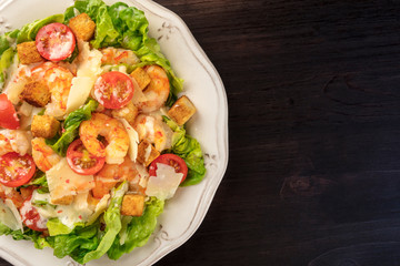 Shrimp Caesar salad with Parmesan cheese, croutons, cherry tomatoes and lettuce, close-up overhead shot with copy space